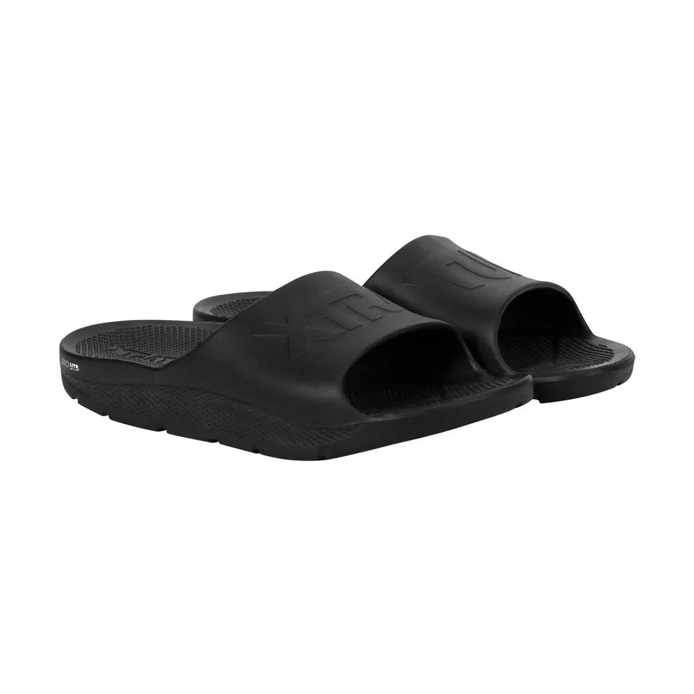 Pair of black Apres Fish slides with textured footbeds and embossed logos.
