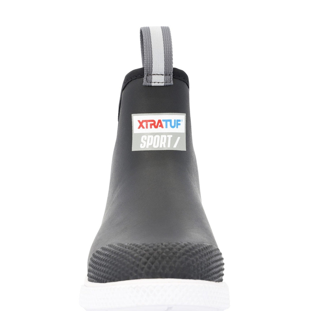 Black XTRATUF Sport 6" ankle deck boot with white sole, textured toe, and reflective pull tab.